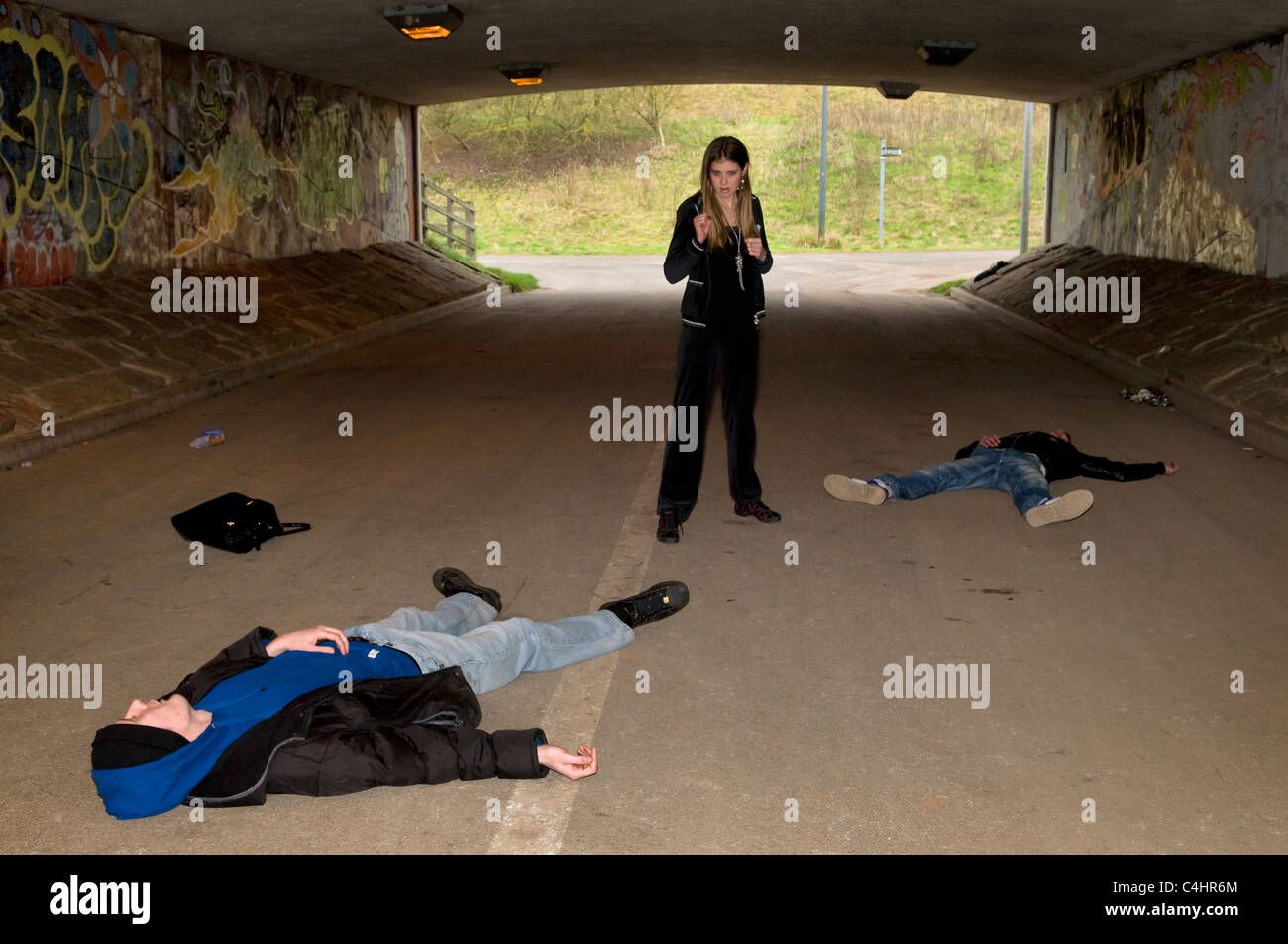 Scene showing young Caucasian woman after defending herself against two male attackers having fought off muggers in underpass Stock Photo