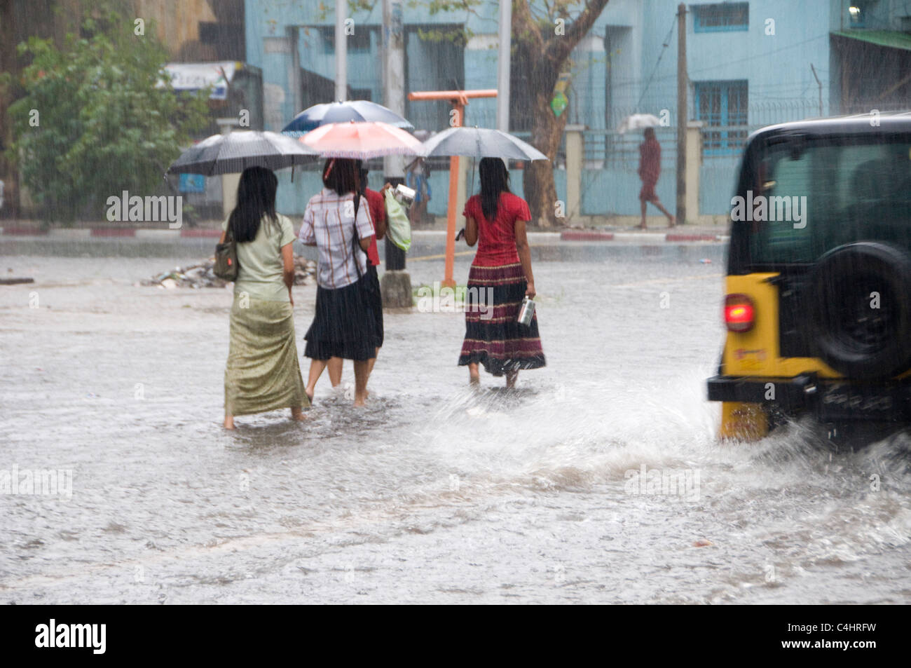 Pedestrians walk with umbrellas in a flooded street due to abundant rainfall in the center of Yangon in Myanmar Stock Photo