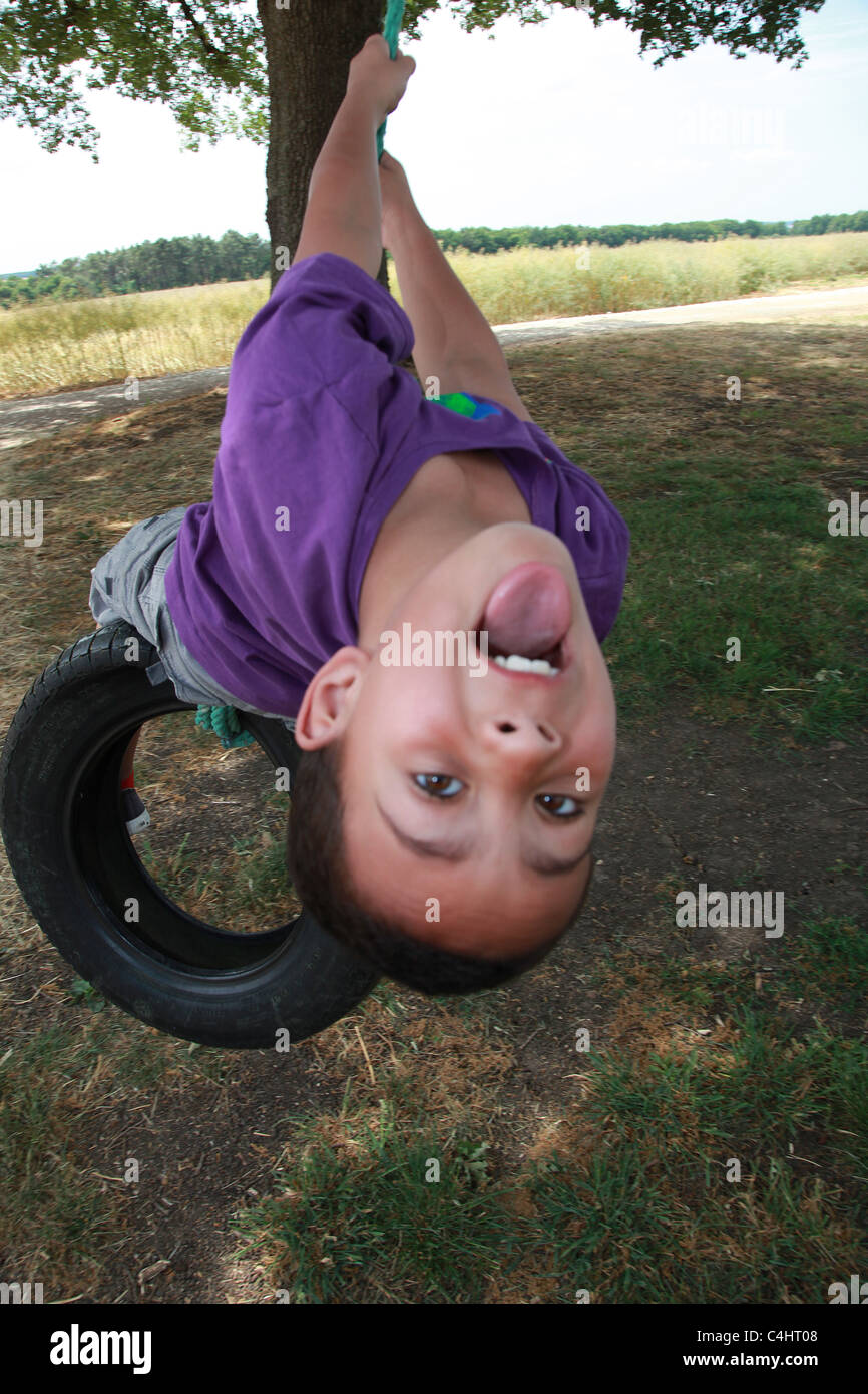 8 year old boy playing on a tyre swing. Stock Photo