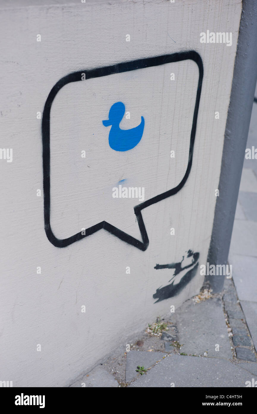 Stencil / graffito on a wall showing a tank, a speech bubble next to the gun and a blue duck located inside the bubble Stock Photo