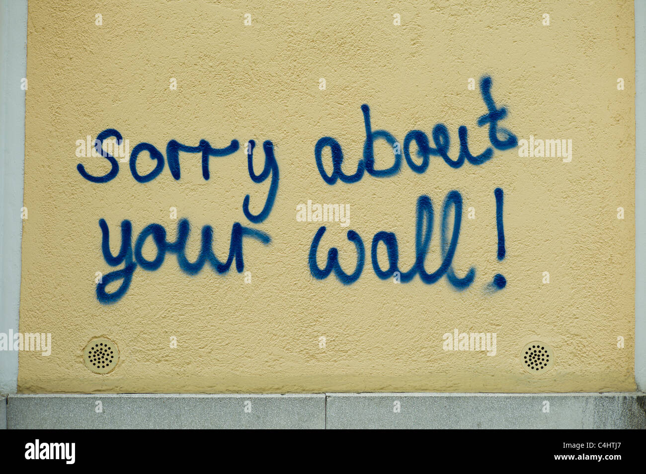 Yellowish wall having the words "sorry about your wall!" sprayed onto it, Munich, Bavaria Stock Photo