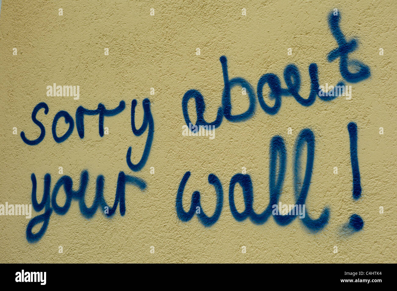 Yellowish wall having the words 'sorry about your wall!' sprayed onto it, Munich, Bavaria Stock Photo