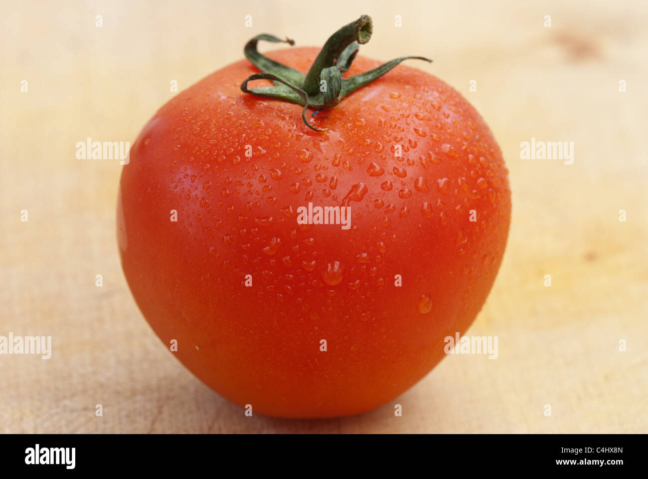 Whole tomato on a wooden board Stock Photo