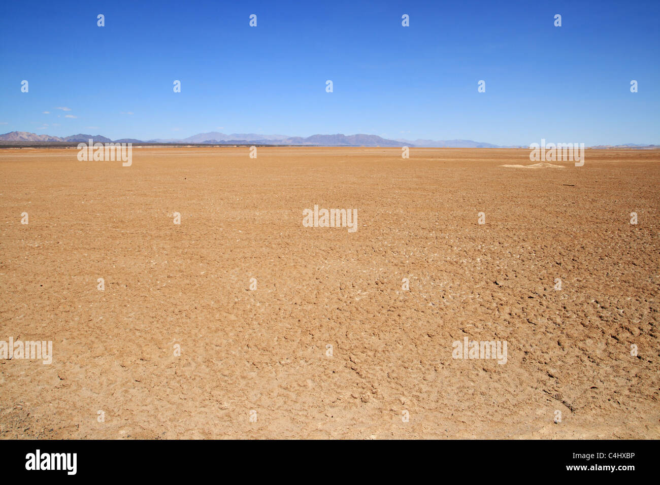flat empty Mojave Desert floor with distant mountains on the horizon Stock Photo