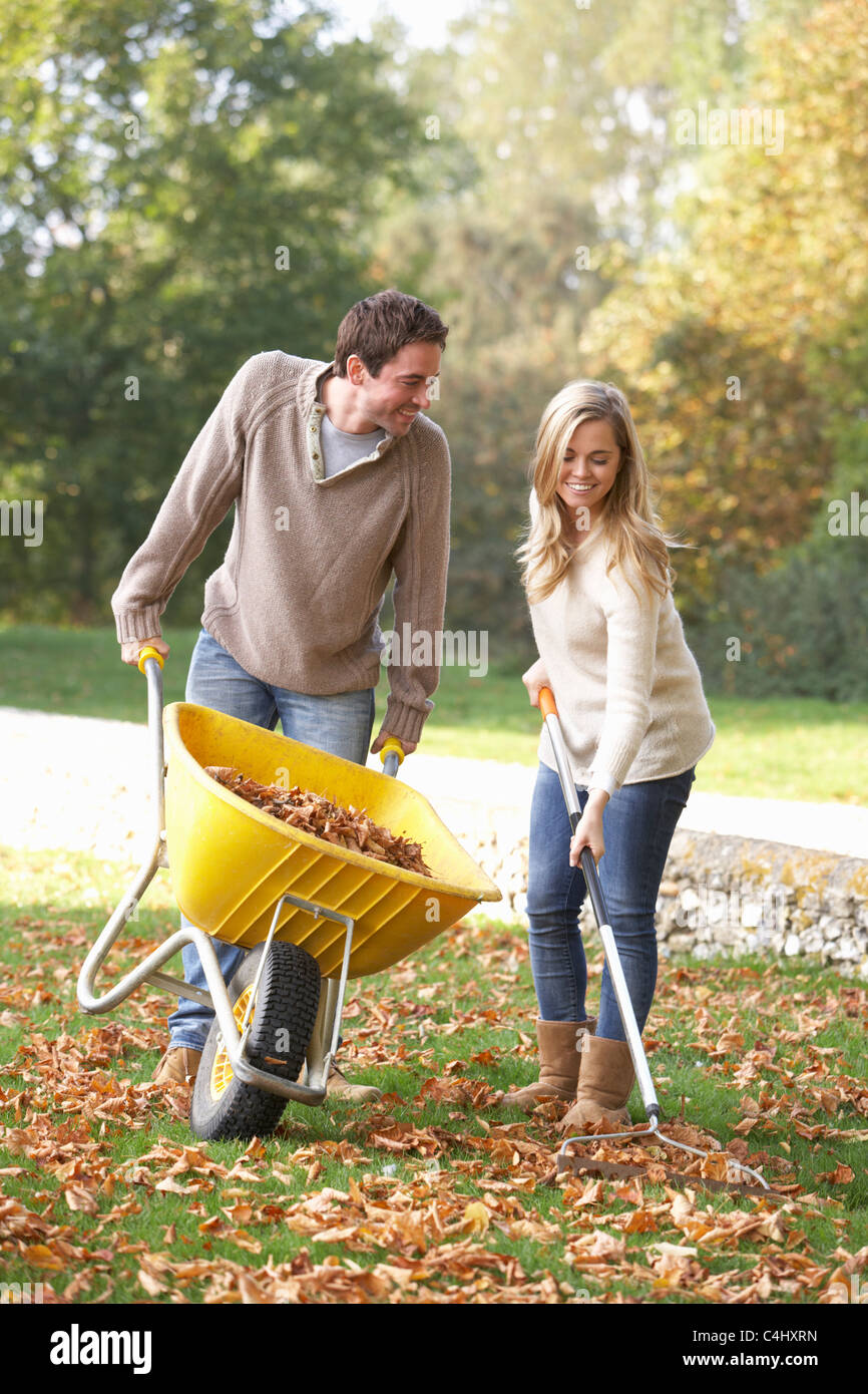 Young couple raking autumn leaves in garden Stock Photo