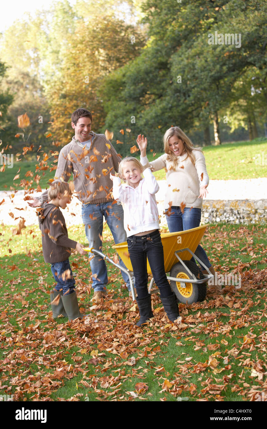 Family throwing autumn leaves into the air in garden Stock Photo