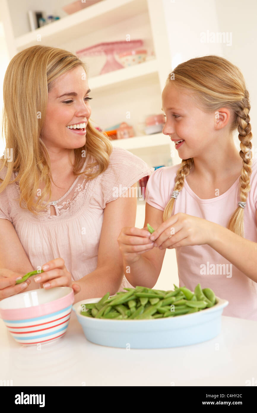 Young woman with child splitting pea in kitchen Stock Photo