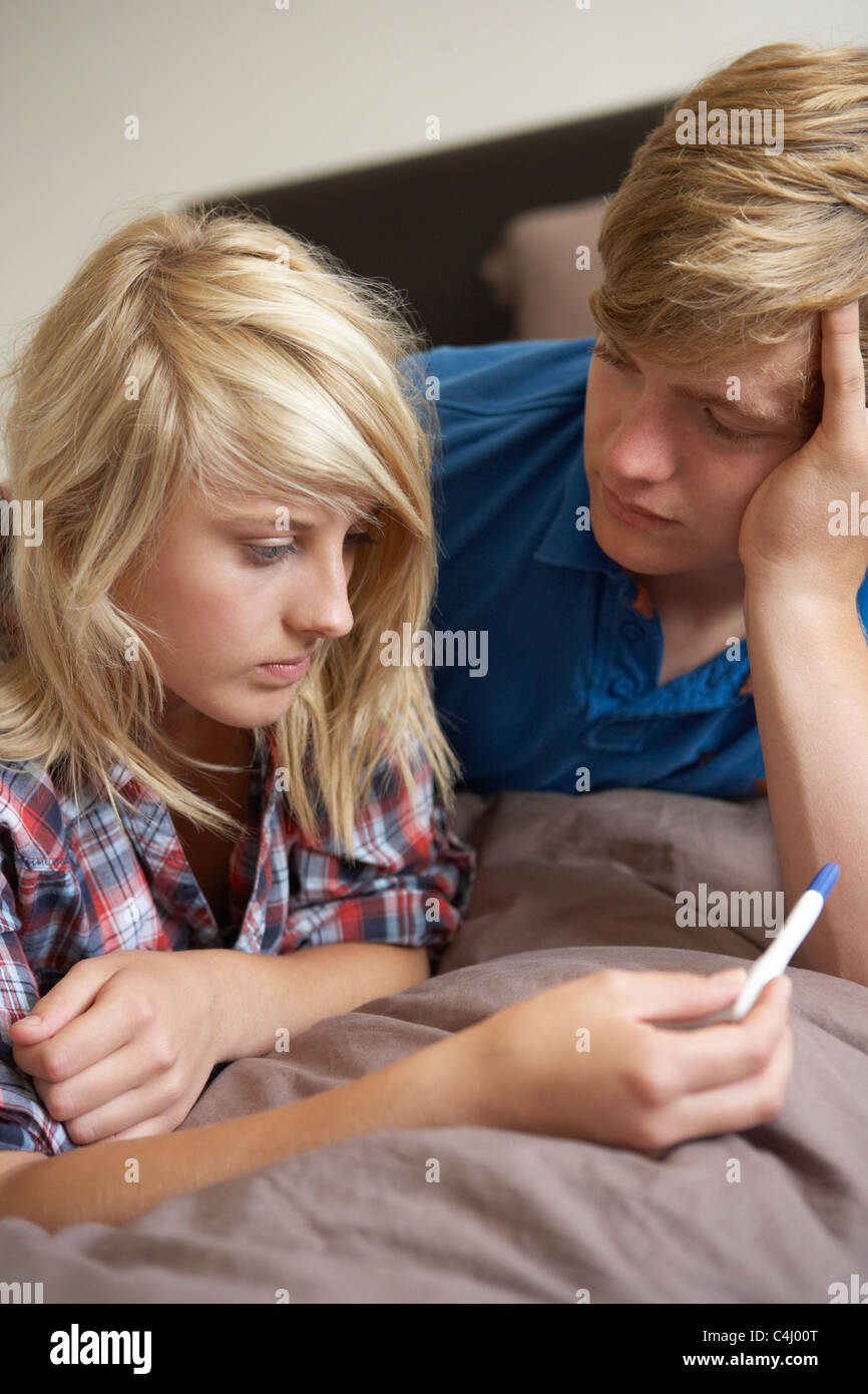 Two Teenage Girls Lying On Bed Looking At Pregnancy Testing Kit Stock Photo