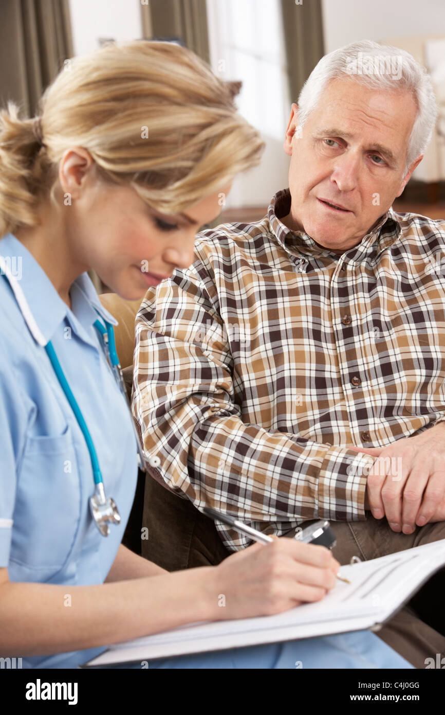 Senior Man Talking To Health Visitor At Home Stock Photo