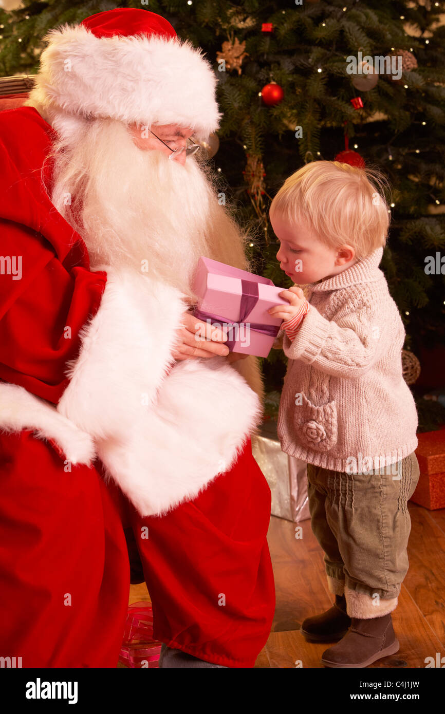 Santa Claus Giving Gift To Boy In Front Of Christmas Tree Stock Photo