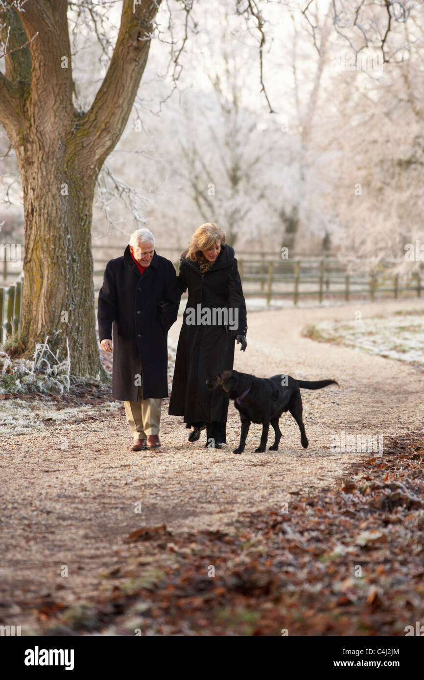Senior Couple On Winter Walk With Dog Through Frosty Landscape Stock Photo