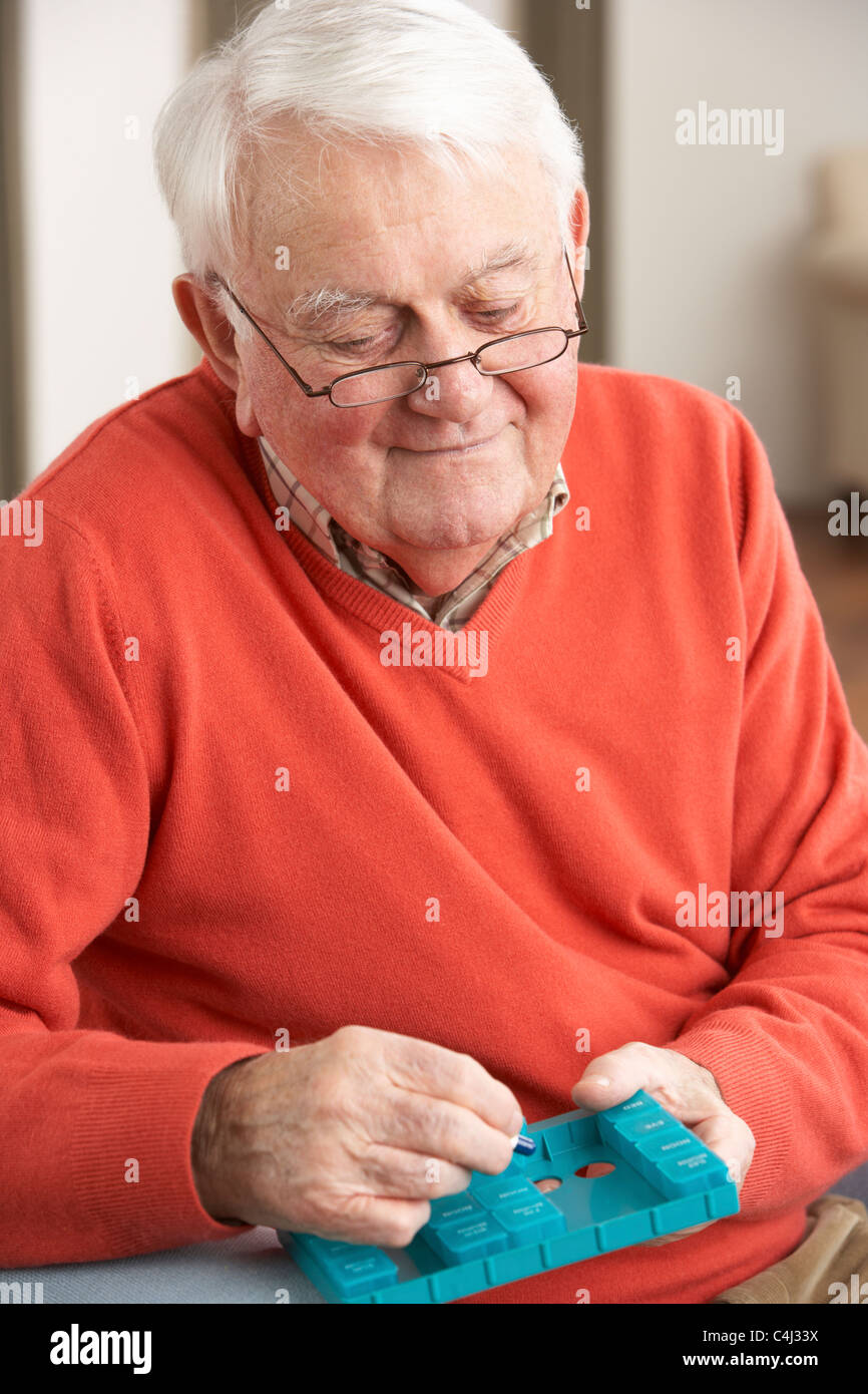 Senior Man Sorting Medication Using Organiser At Home Stock Photo