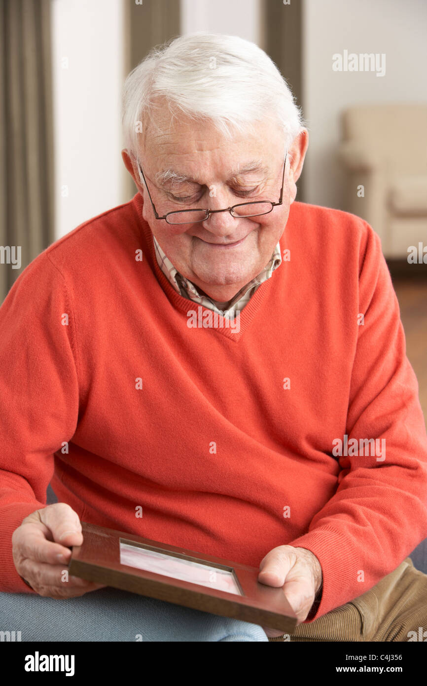 Senior Man Looking At Photograph In Frame Stock Photo