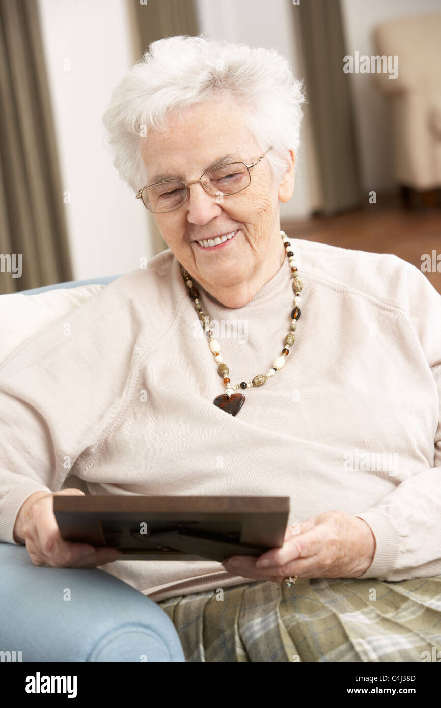 Senior Woman Looking At Photograph In Frame Stock Photo