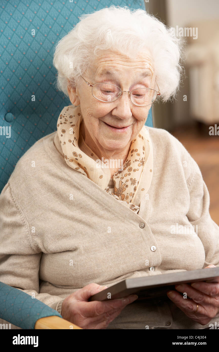 Senior Woman Looking At Photograph In Frame Stock Photo