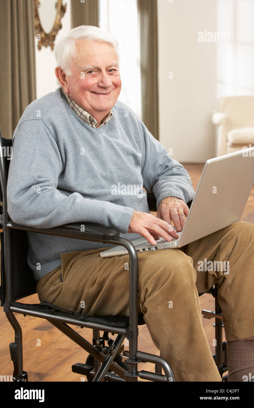 Disabled Senior Man Sitting In Wheelchair Using Laptop Stock Photo