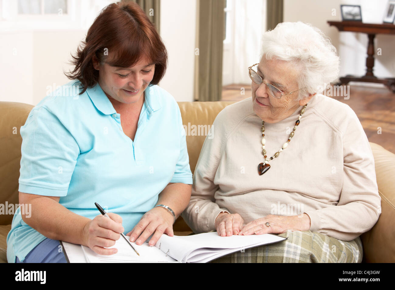 Senior Woman In Discussion With Health Visitor At Home Stock Photo