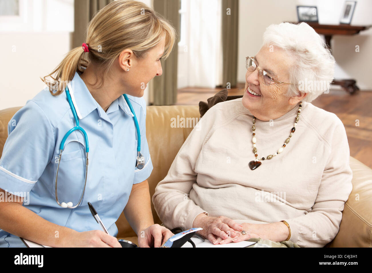 Senior Woman In Discussion With Health Visitor At Home Stock Photo