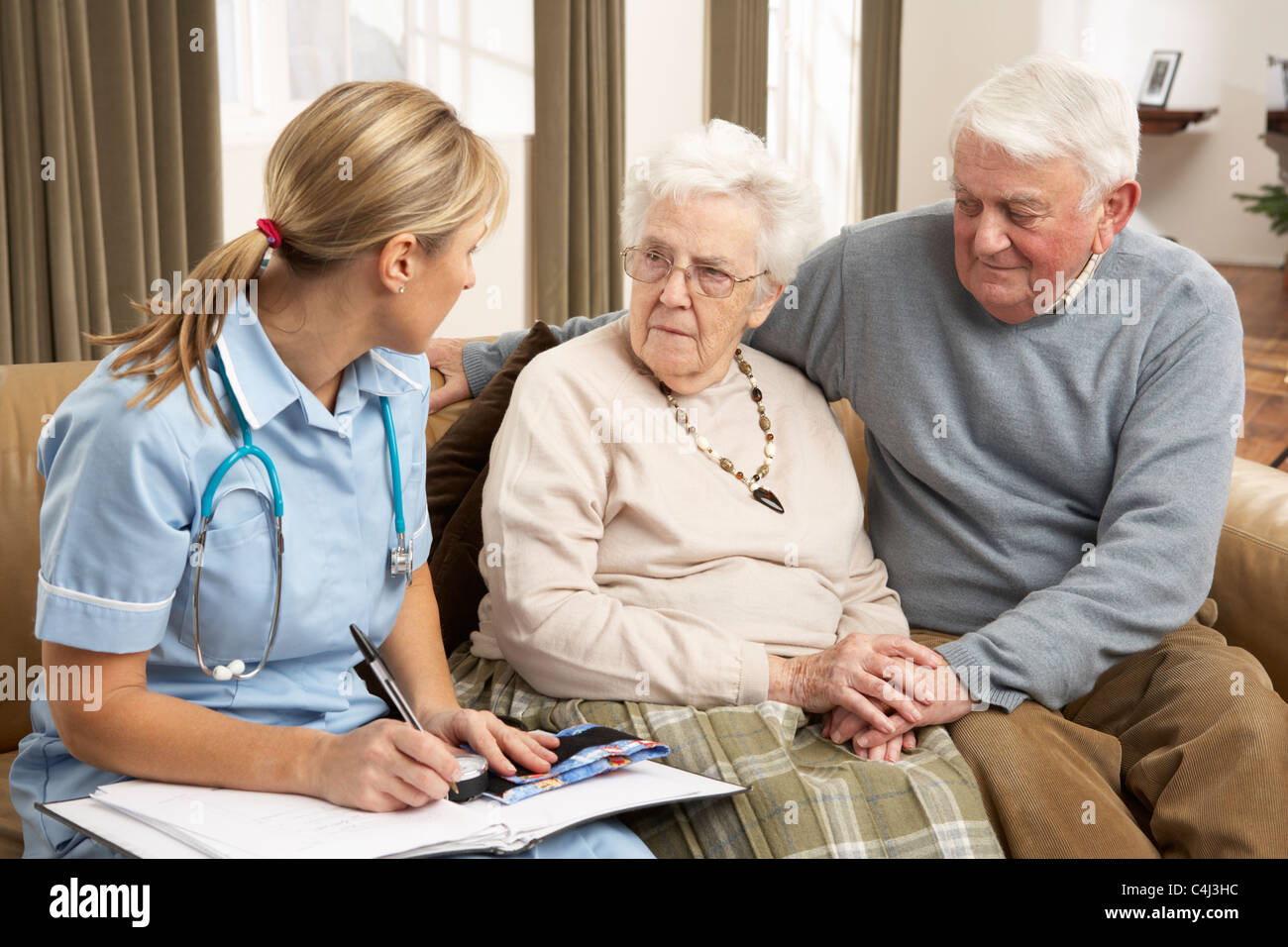 Senior Couple In Discussion With Health Visitor At Home Stock Photo