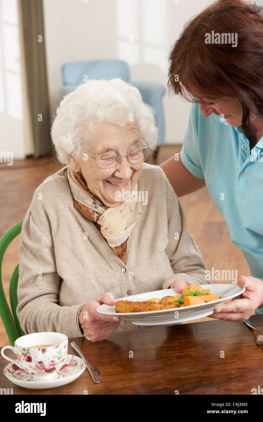 Senior Woman Being Served Meal By Carer Stock Photo