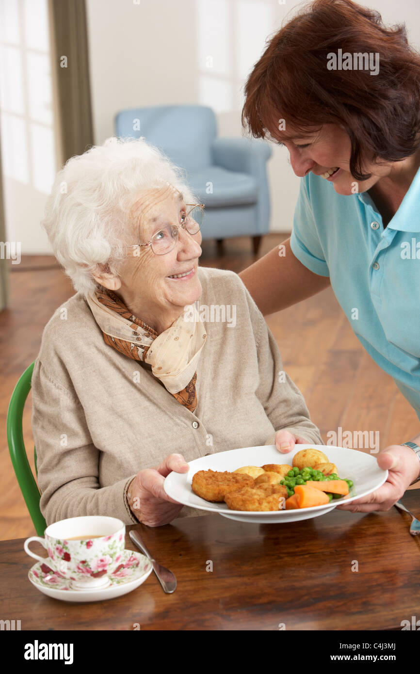 Senior Woman Being Served Meal By Carer Stock Photo