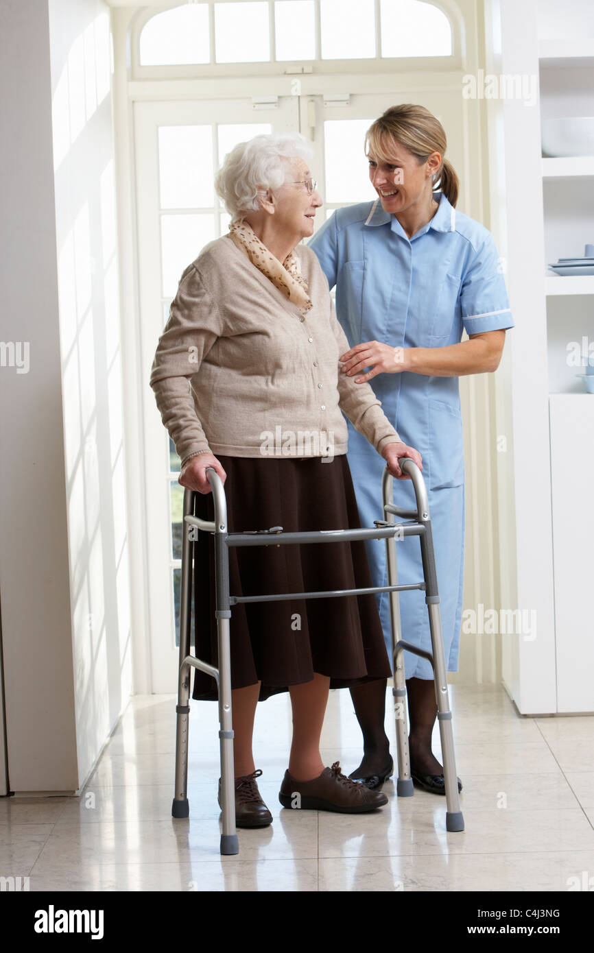 Carer Helping Elderly Senior Woman Using Walking Frame Stock Photo