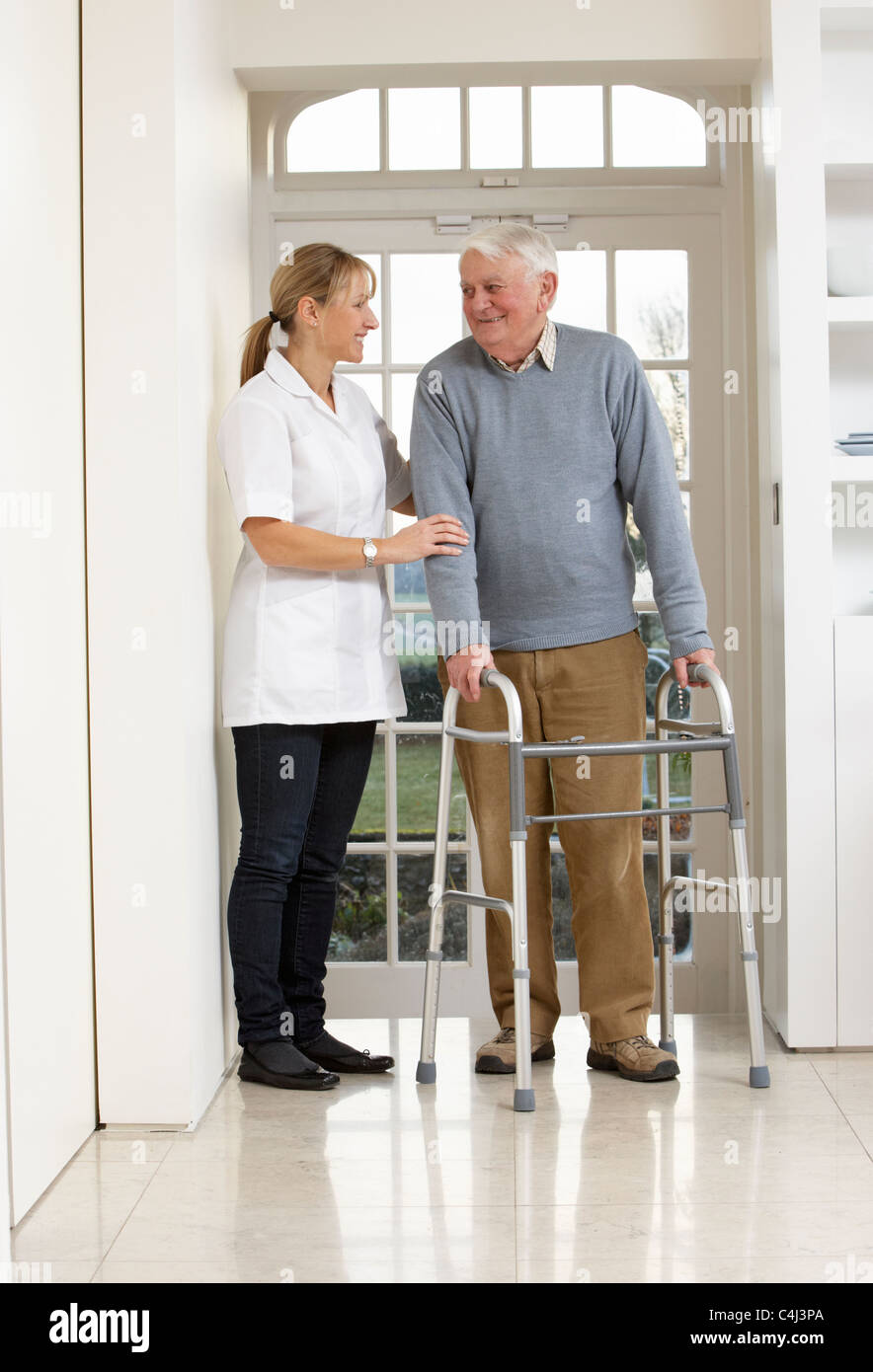Carer Helping Elderly Senior Man Using Walking Frame Stock Photo