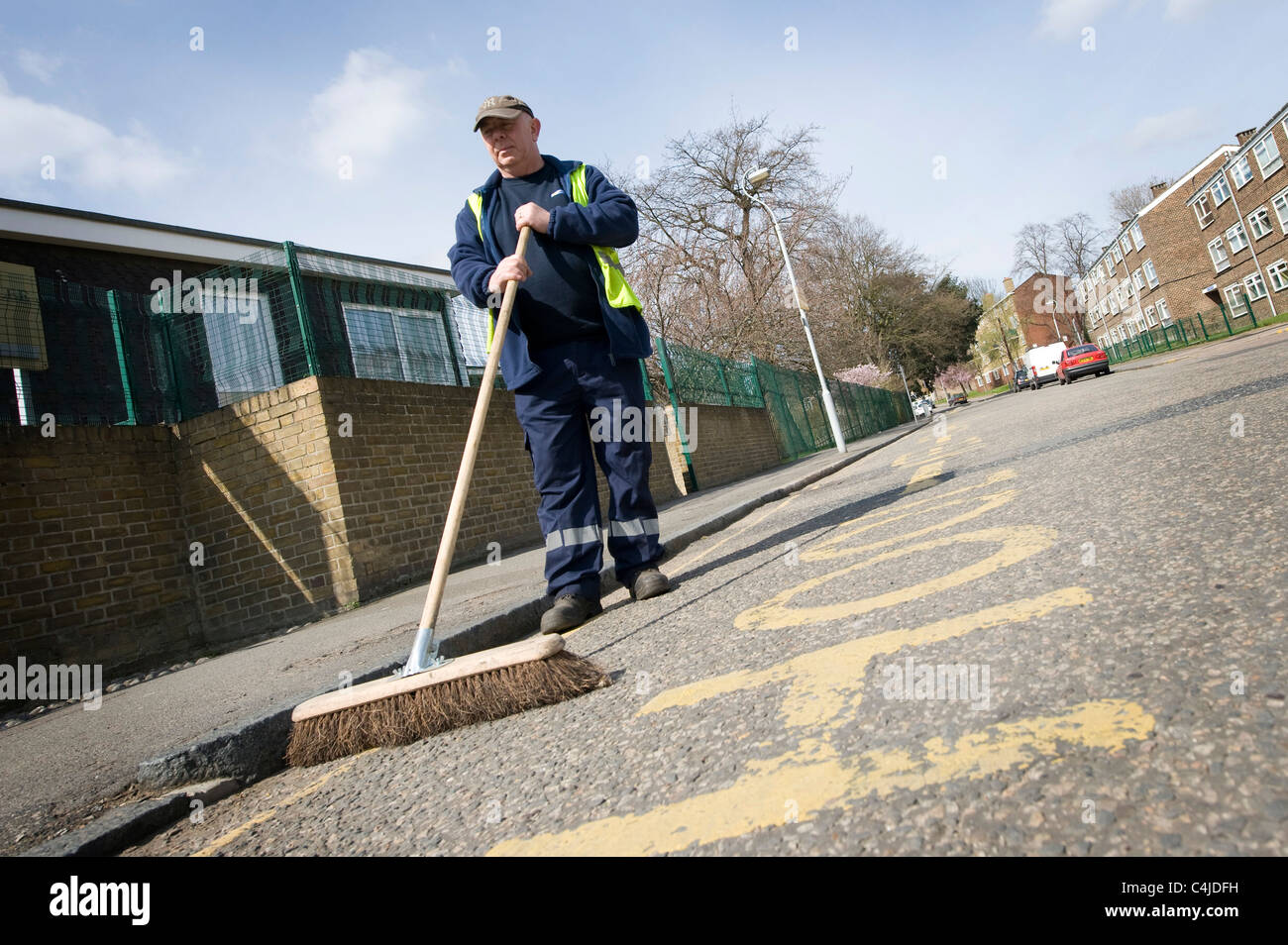 Council worker sweeping a street in a suburban area of England Stock