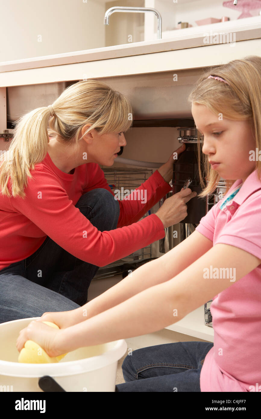 Daughter Helping Mother To Mop Up Leaking Sink Stock Photo