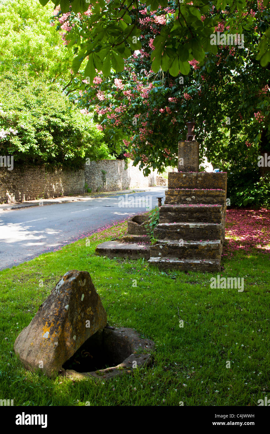 A stone mounting block in the pretty Cotswold village of Shilton, Oxfordshire, England, UK on a sunny day in spring Stock Photo
