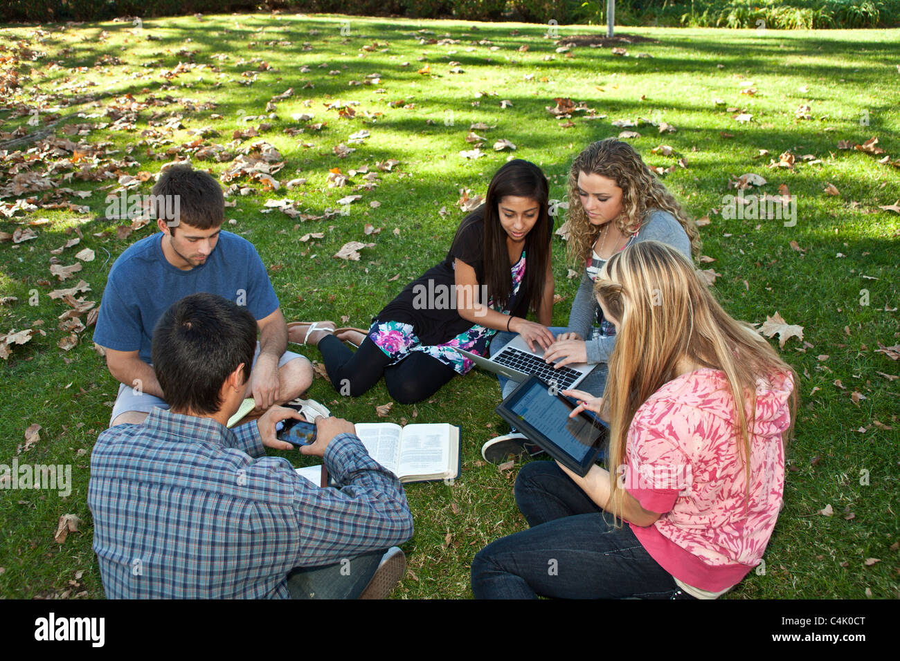 Multi ethnic Ethnically diverse discussion  group  teens study together using mobile phone iPhone iPad devices. MR © Myrleen Pearson Stock Photo