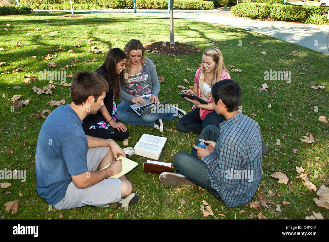 Multi ethnic racial racially Ethnically diverse discussion group teens study together using iPad mobile phone iPhone devices. MR © Myrleen Pearson Stock Photo