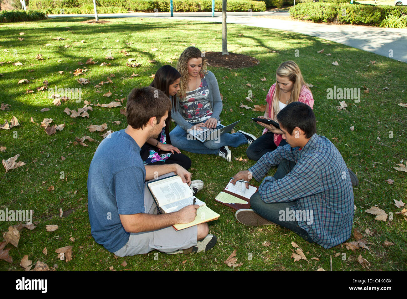 Multi ethnic racial minority Ethnically diverse discussion group teens study together using mobile phone iPhone iPad  devices. MR © Myrleen Pearson Stock Photo