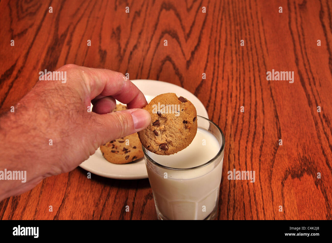 A bout to dunk a cookie, in a cool glass of milk Stock Photo