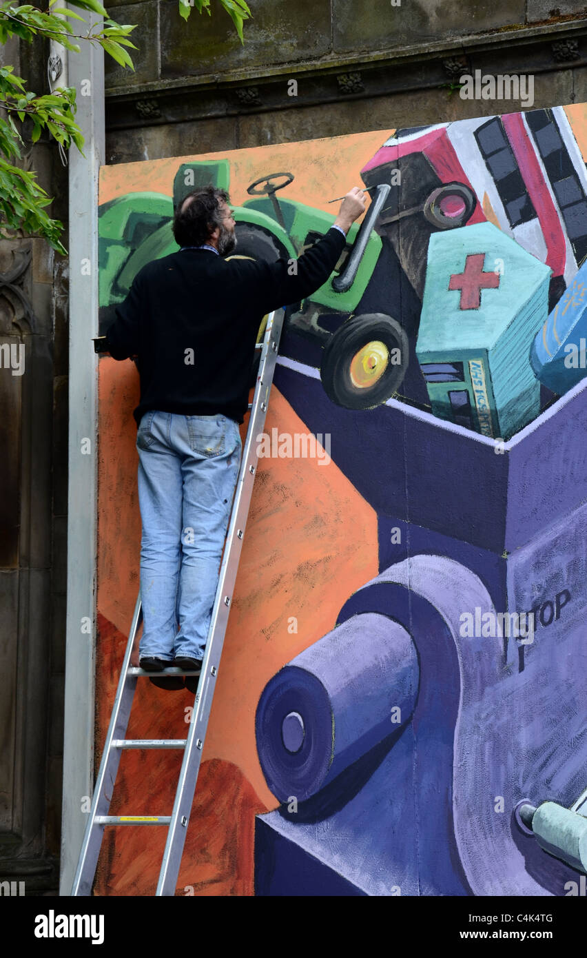 Artist painting a topical mural at St John's Church at the West End of Princes Street in Edinburgh, Scotland. Stock Photo