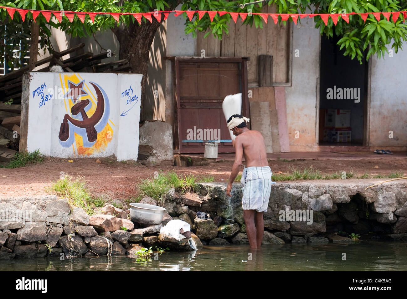 Man washing clothes in backwaters of Alleppey (Alappuzha), Kerala, India Stock Photo