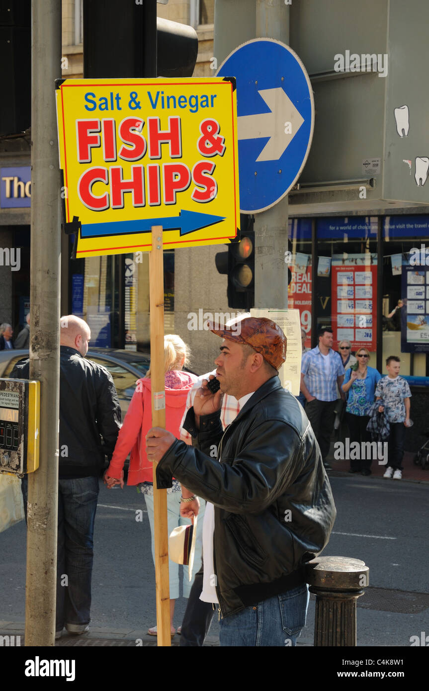 Man holding a sign giving directions to a fish and chip shop, York, North Yorkshire, England Stock Photo