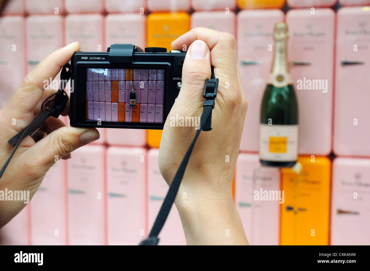 A photographer's hands taking a picture of a champagne display in a shop window Stock Photo