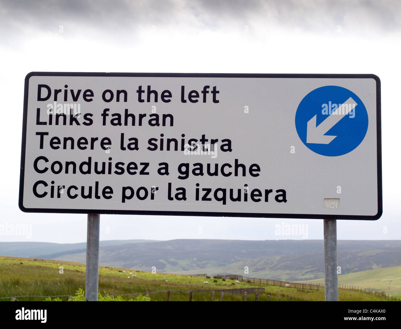 A sign on the border telling drivers to drive on the left. although driving on the left is the law in both countries. Stock Photo