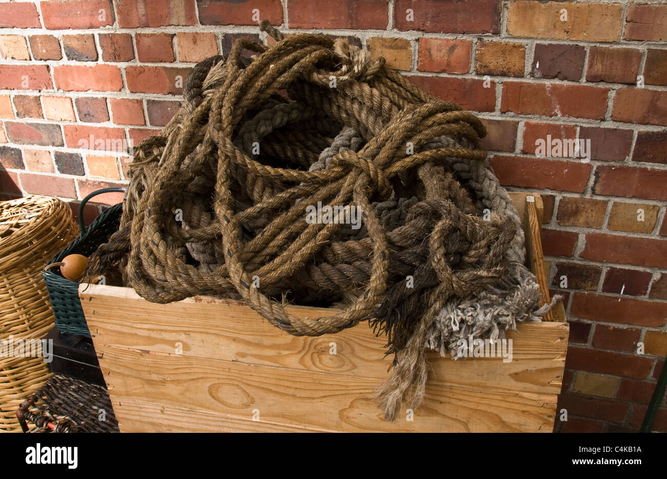 Hanks of old rope in a wooden box in front of a brick wall Stock Photo