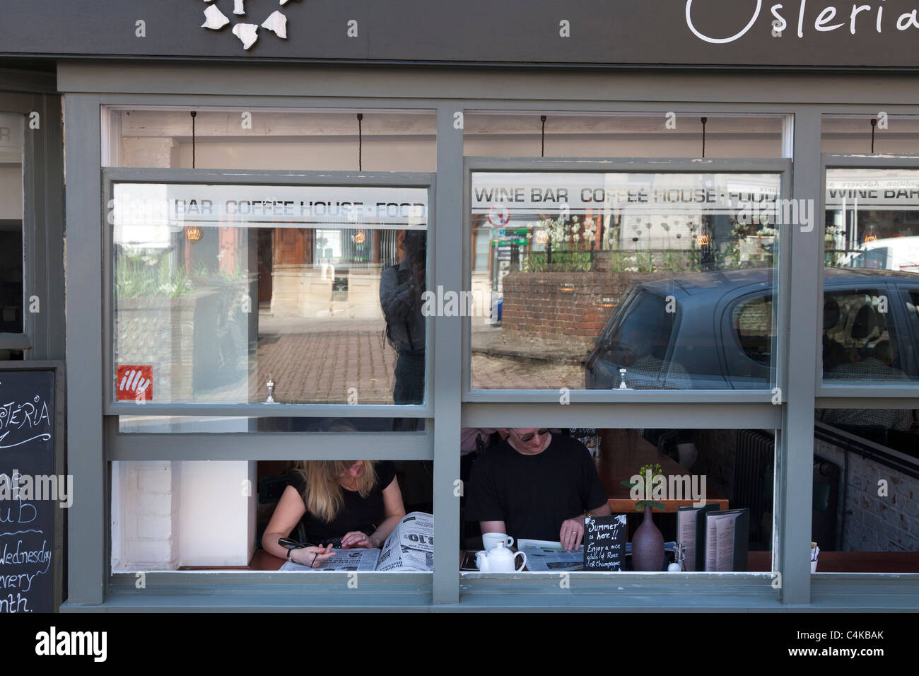 Open windows to street plus people in cafe reading newspaper Stock Photo