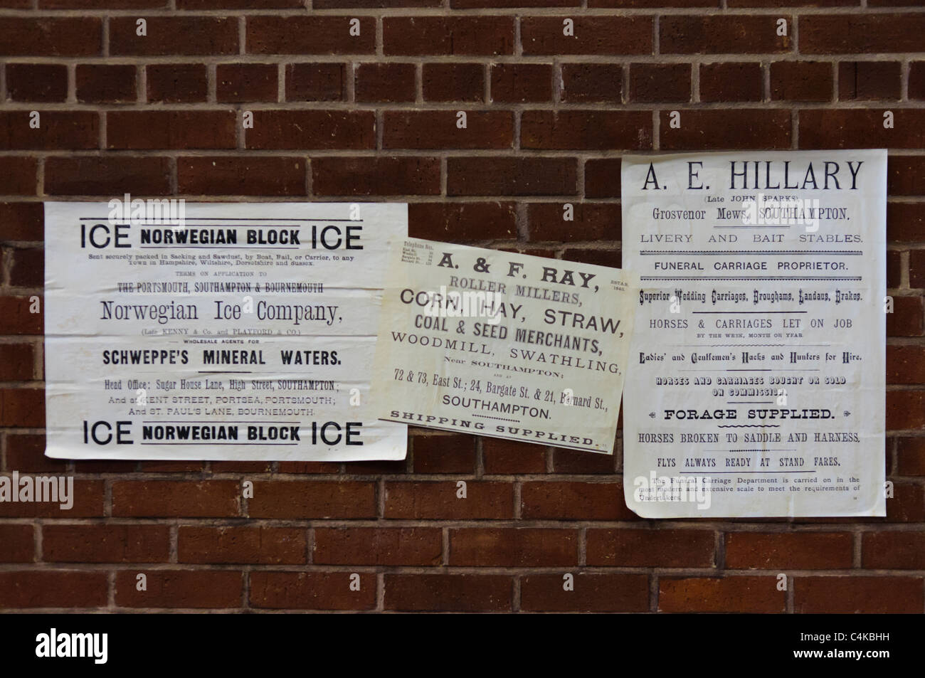 Old fashioned fly posters on a brick wall: Norwegian Ice Company, Corn and Hay millers, Funeral providers. Stock Photo