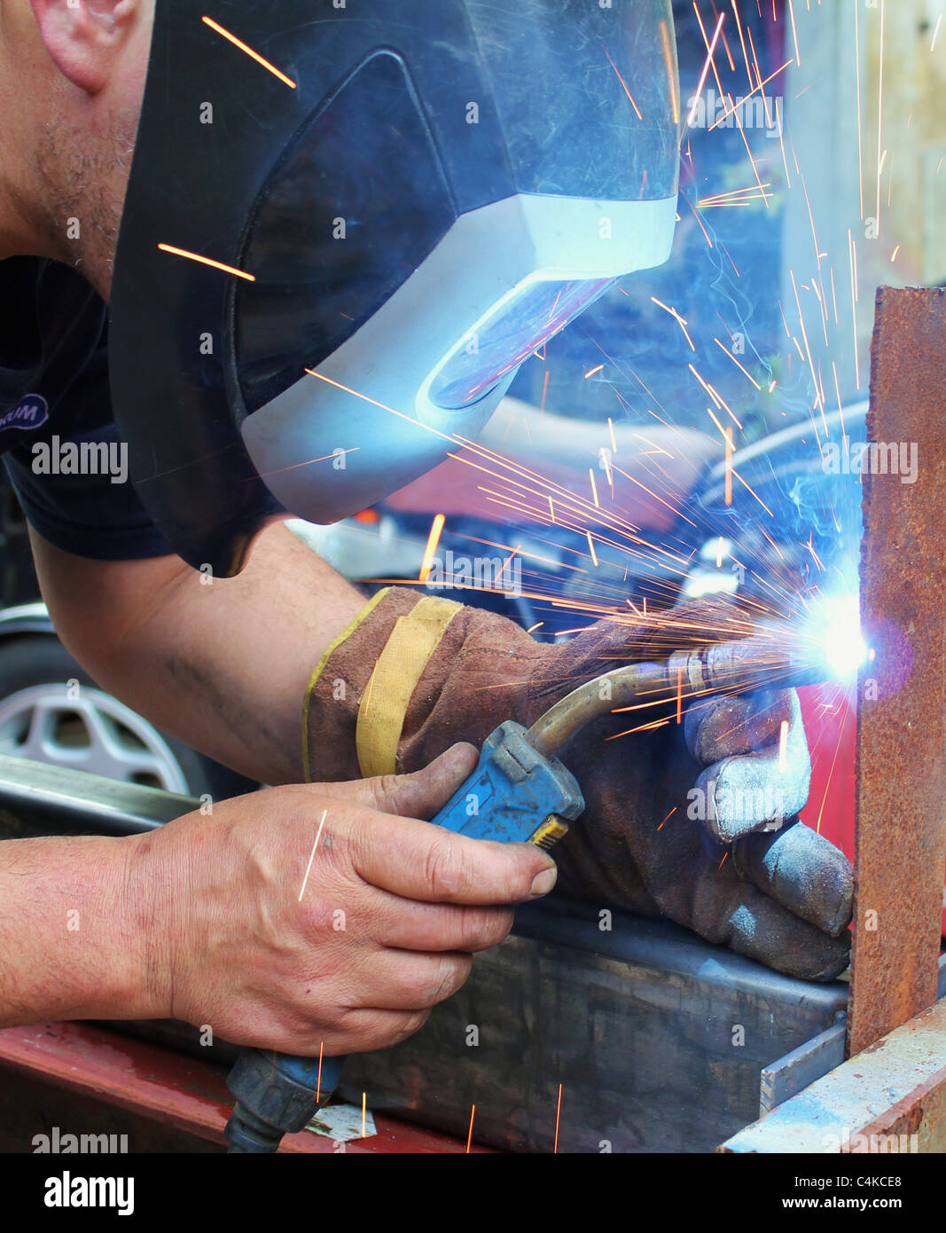 Arc welder wearing welding mask with welding sparks Stock Photo