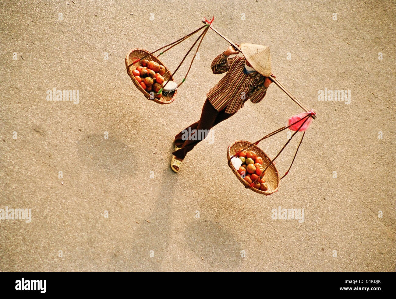 Vietnamese woman carrying trays of fruit and vegetables suspended from