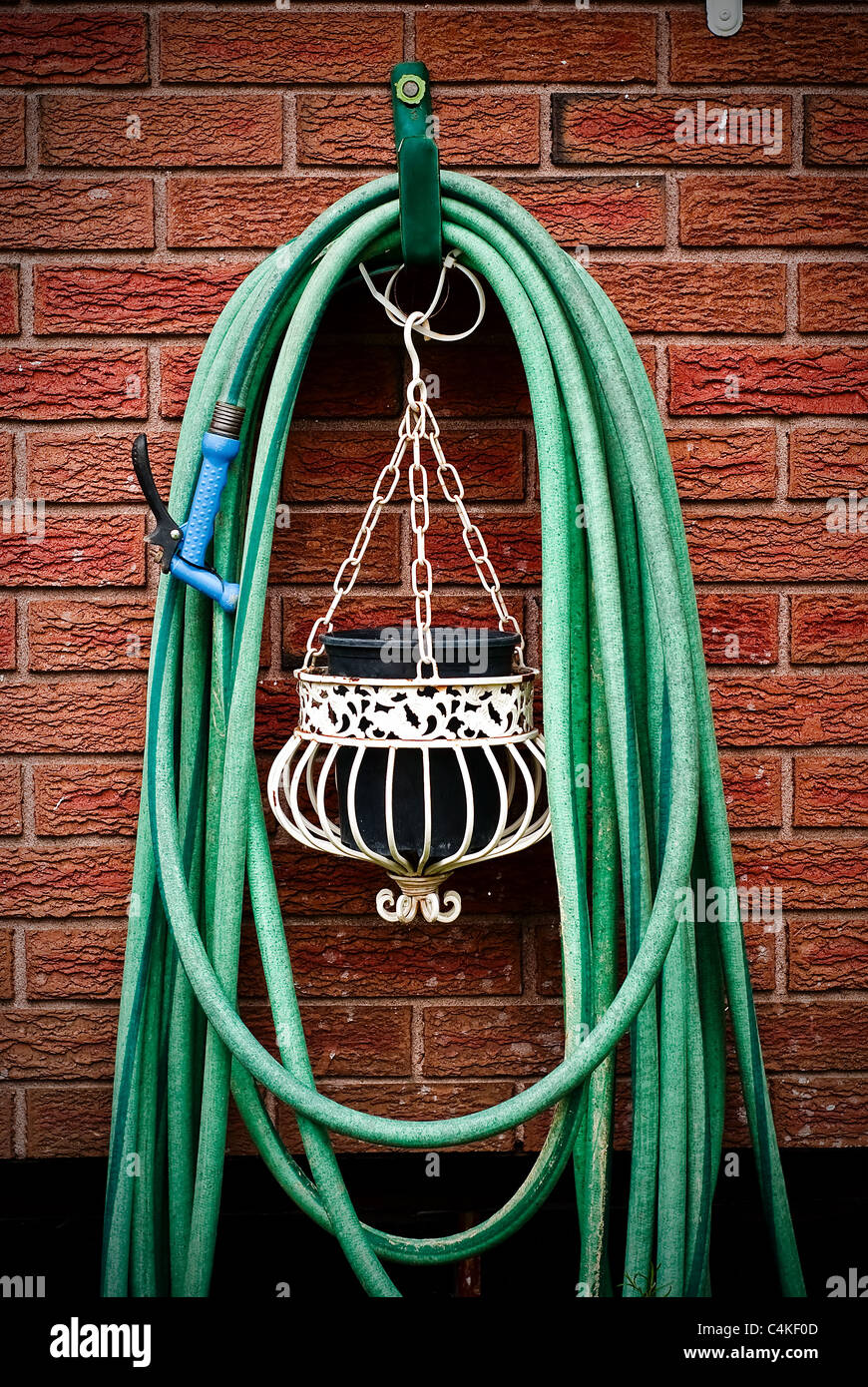 A common home garden hose coiled up and hanging on brick wall with