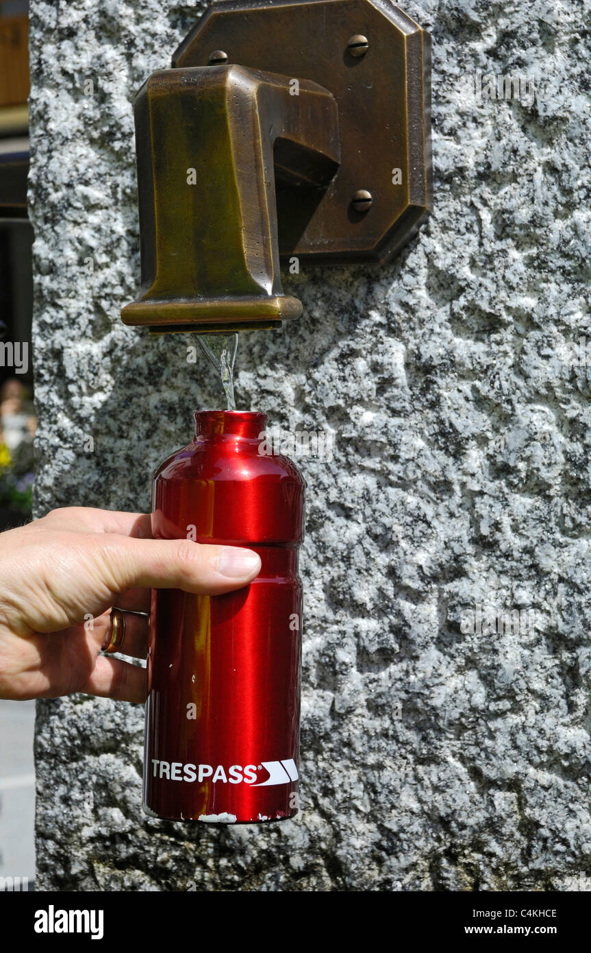 Filling up metal drinks bottle with cool spring fresh water from a drinking fountain. Stock Photo