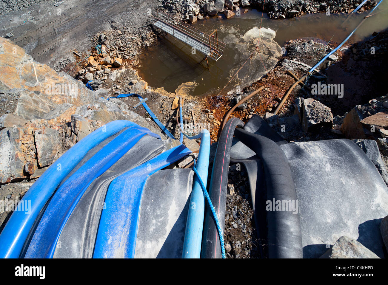 Water hoses going into bottom of a rock quarry , used to pump of the