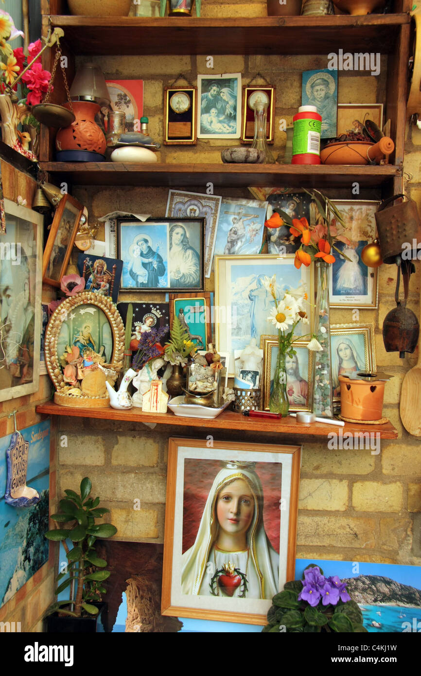 roman catholic images, items and souvenirs on shelves in Italian home England Stock Photo