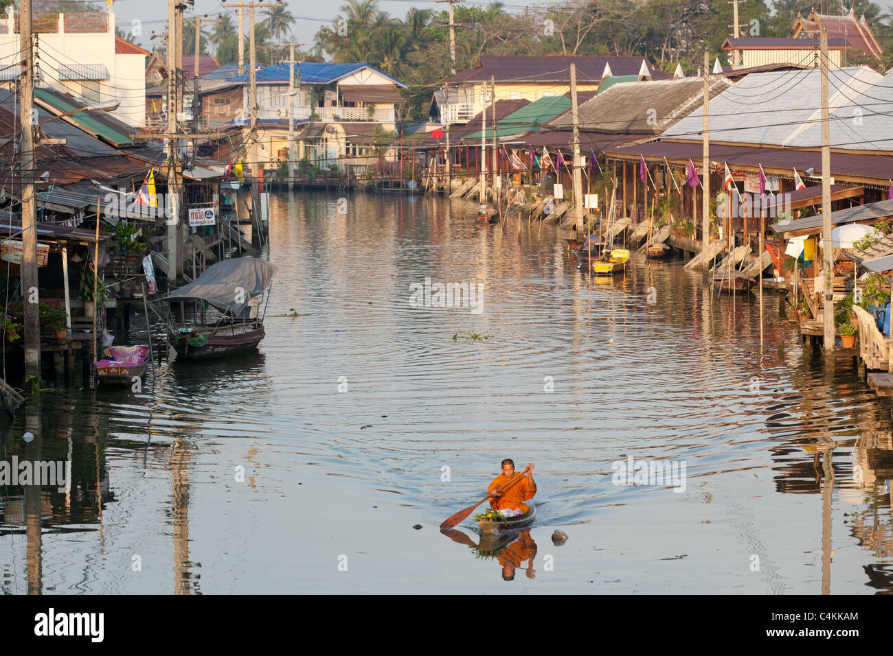 Thai Buddhist monk rowing rowboat in Amphawa floating market, early in ...