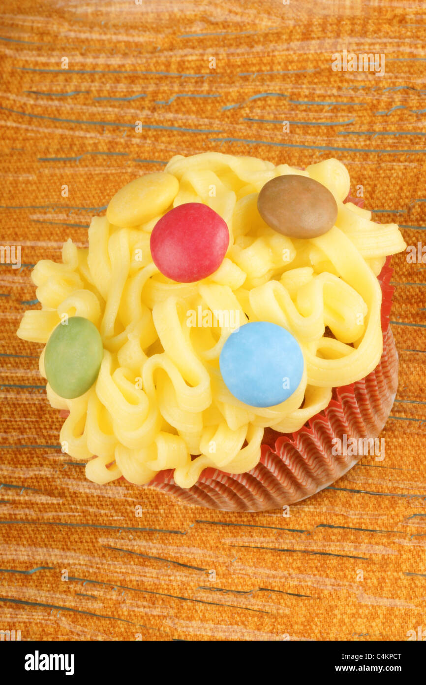 Fancy yellow cupcake decorated with small colorful sugarcoated